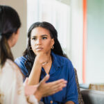 During a counseling session, the  unrecognizable mid adult female patient gestures while speaking.  The mid adult female therapist listens attentively.